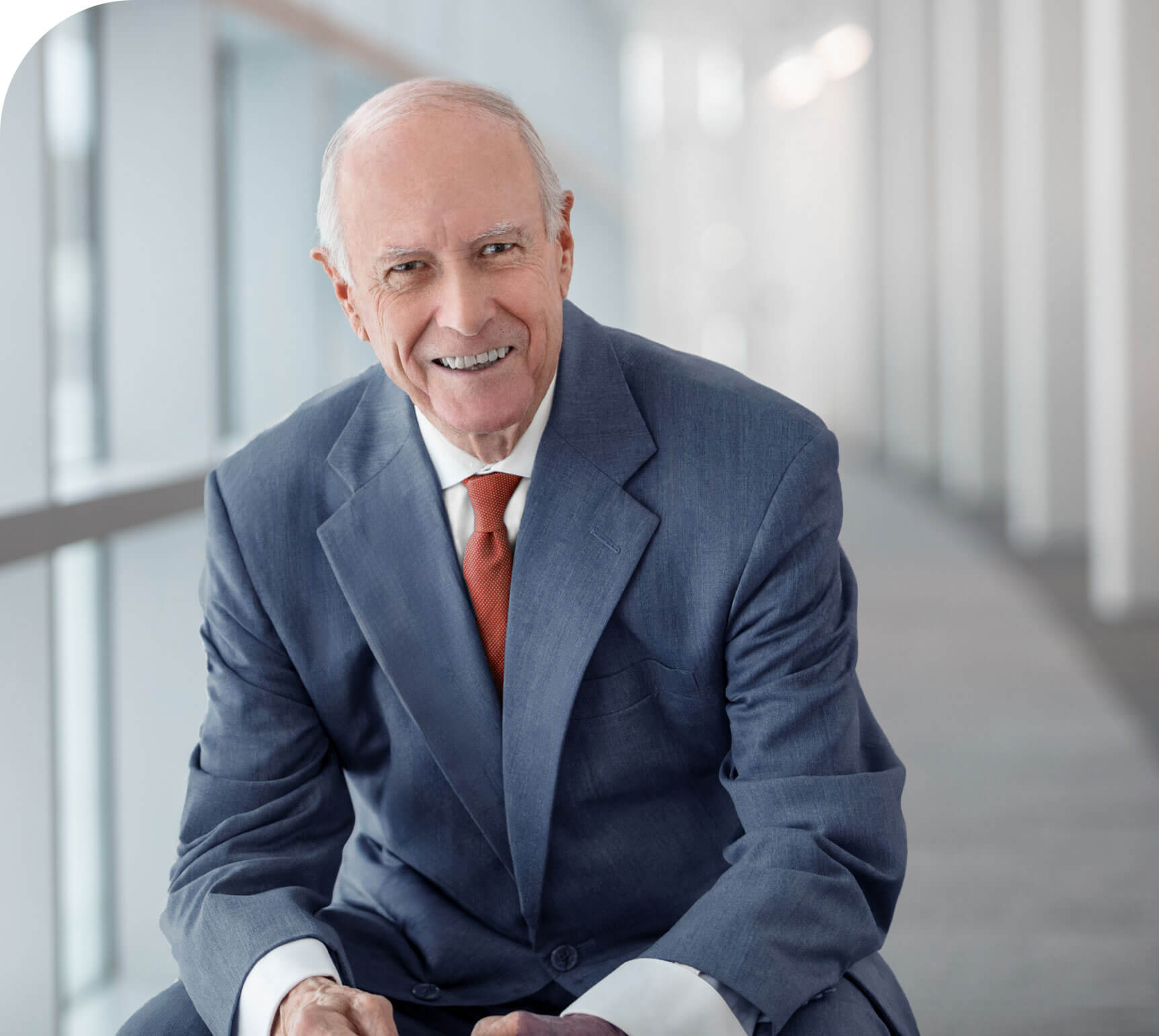 A photo of Richard George in a blue suit, red tie and smiling