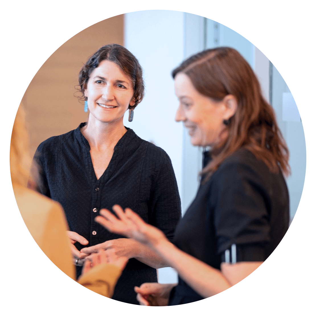 A photo of Jessa Valentine with Bethany Miller in the foreground. Jessa is smiling and Bethany is explaining something while gesturing with her hands.