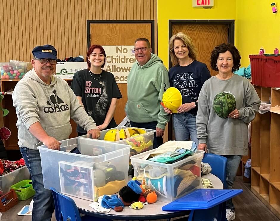 Two women are working and smiling while preparing spaghetti in a kitchen.