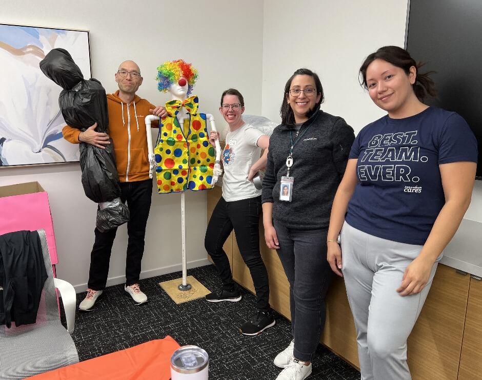 Two women are working and smiling while preparing spaghetti in a kitchen.