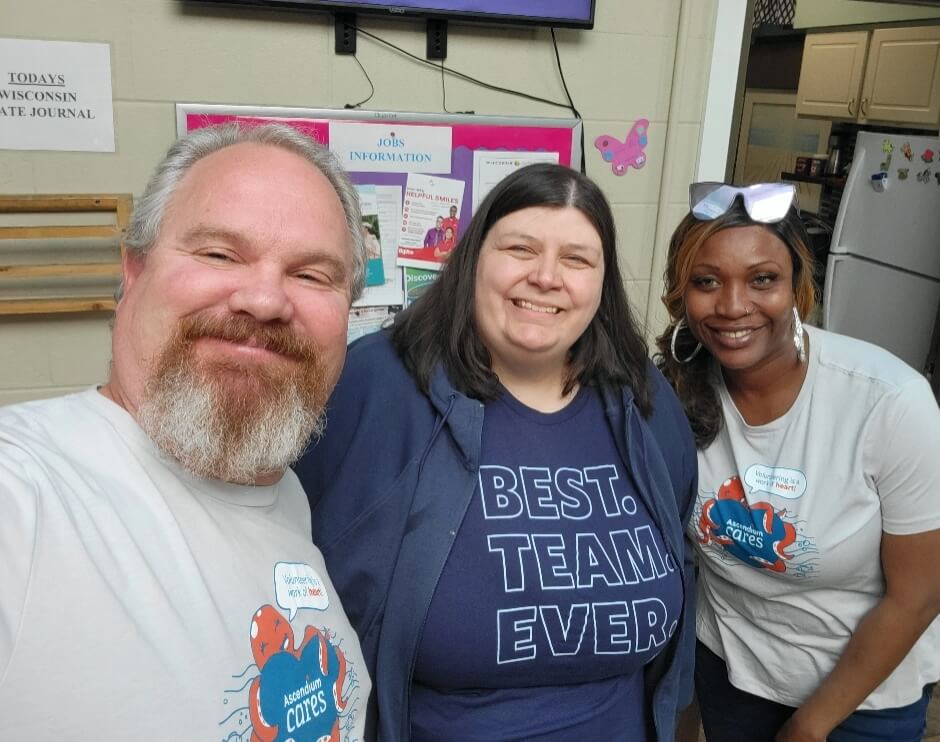 Two women are working and smiling while preparing spaghetti in a kitchen.