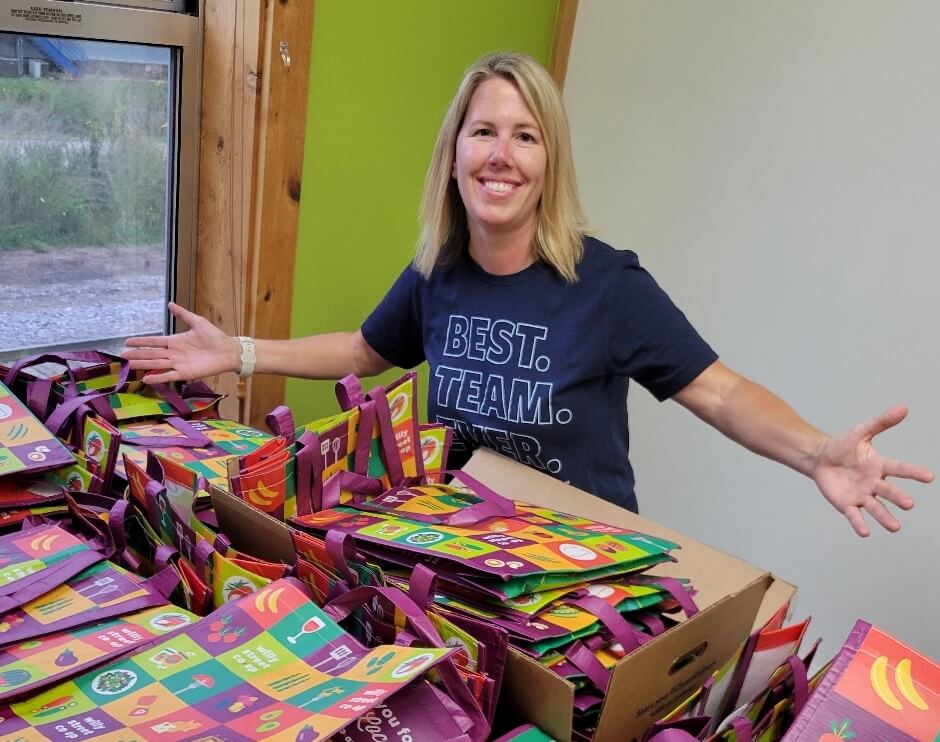 Two women are working and smiling while preparing spaghetti in a kitchen.