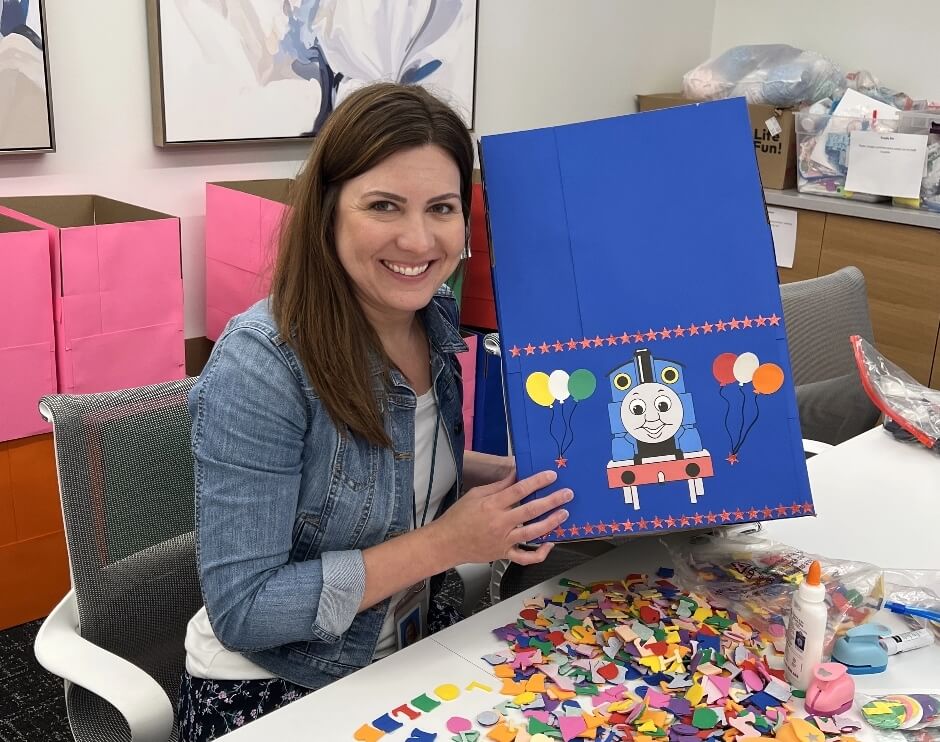 Two women are working and smiling while preparing spaghetti in a kitchen.