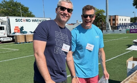 Two happy Ascendium employees voluteer outdoors on a bright sunny day