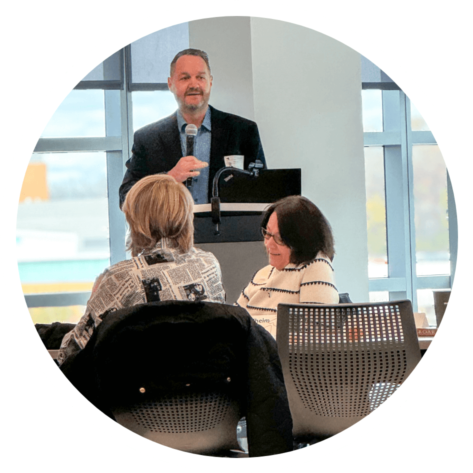 A photo of Jessa Valentine with Bethany Miller in the foreground. Jessa is smiling and Bethany is explaining something while gesturing with her hands.